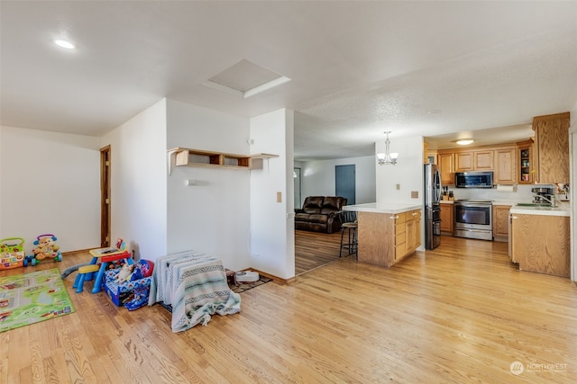 kitchen with pendant lighting, sink, stainless steel appliances, and light hardwood / wood-style floors