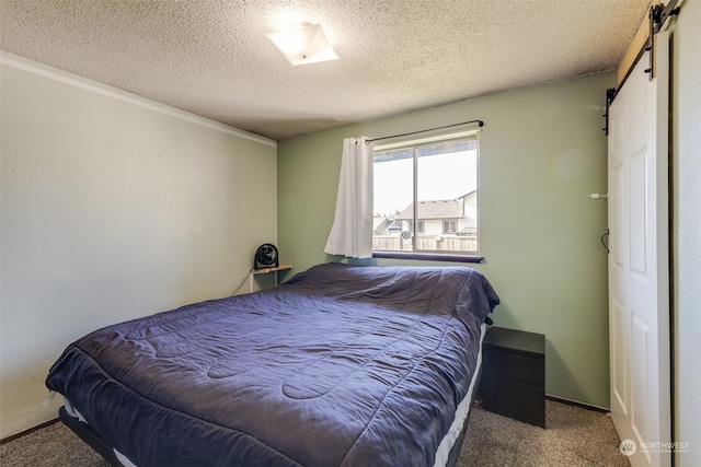 bedroom featuring a barn door, carpet, and a textured ceiling