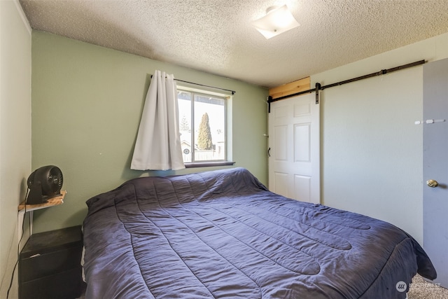 bedroom with a barn door and a textured ceiling