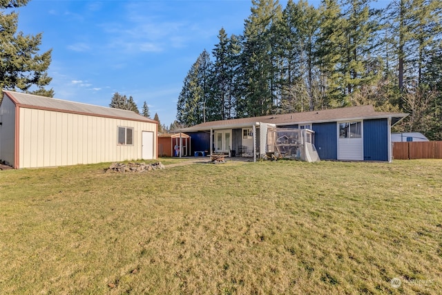 back of property featuring an outdoor structure and a yard