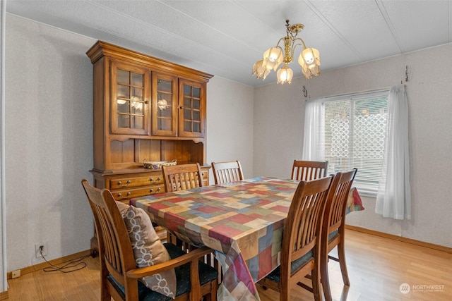 dining area with light hardwood / wood-style flooring and an inviting chandelier