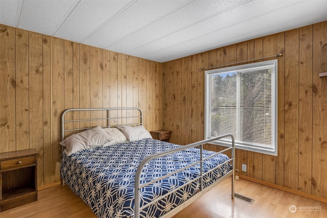 bedroom featuring hardwood / wood-style floors and wooden walls