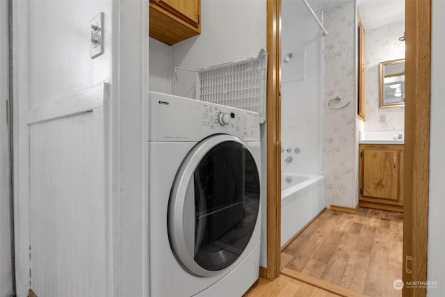 washroom with washer / dryer and light hardwood / wood-style flooring