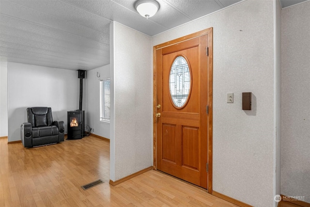 entrance foyer featuring a wood stove and light hardwood / wood-style floors