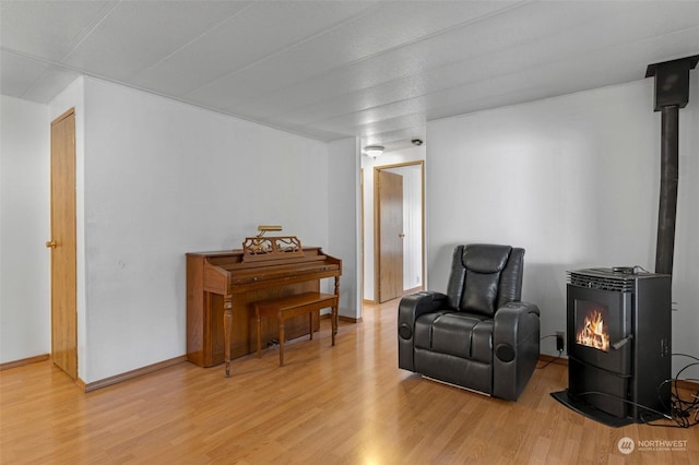 sitting room with a wood stove and light wood-type flooring