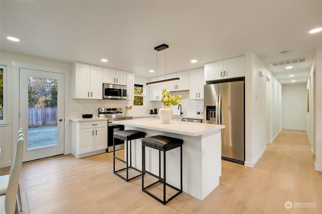 kitchen with white cabinets, stainless steel appliances, and a kitchen island