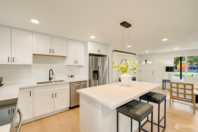 kitchen with pendant lighting, sink, white cabinetry, a center island, and stainless steel appliances