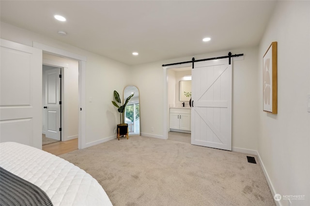 carpeted bedroom featuring connected bathroom and a barn door