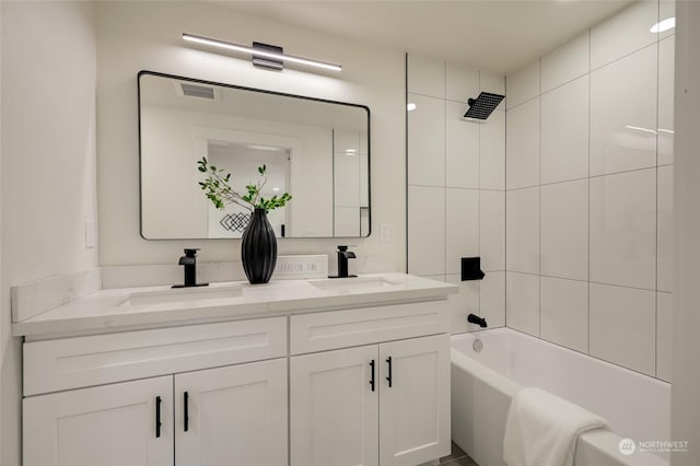 bathroom with tiled shower / bath combo and vanity