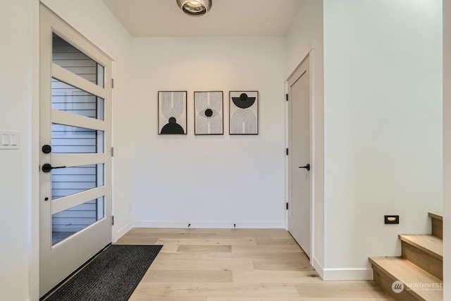 doorway to outside featuring baseboards and light wood-type flooring