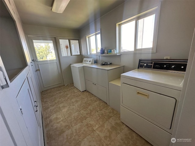 clothes washing area with cabinets and separate washer and dryer