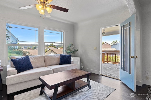 living room with ceiling fan, a textured ceiling, and wood-type flooring