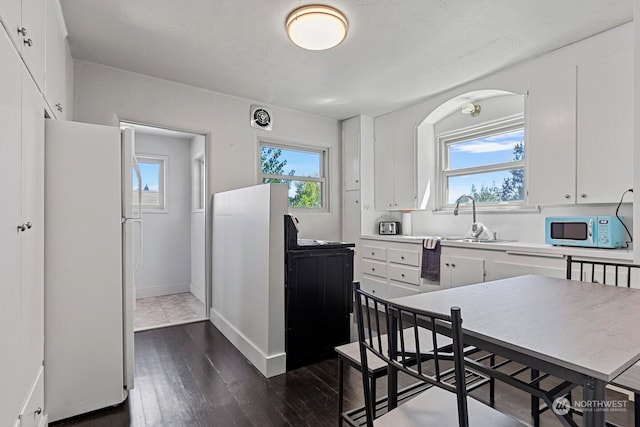 kitchen featuring dark wood-type flooring, plenty of natural light, white cabinets, and white refrigerator