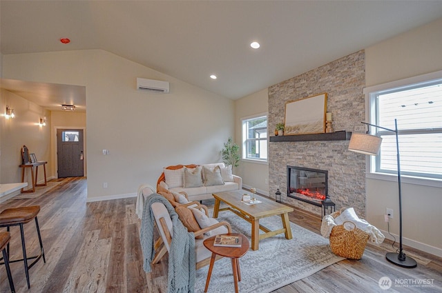 living room with lofted ceiling, baseboards, wood finished floors, and a stone fireplace