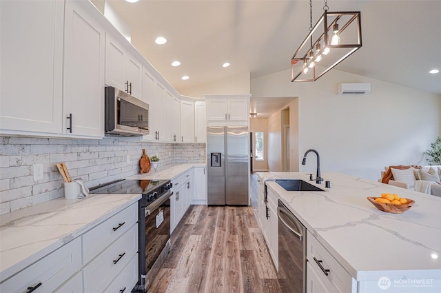 kitchen with hanging light fixtures, light stone countertops, appliances with stainless steel finishes, and white cabinets