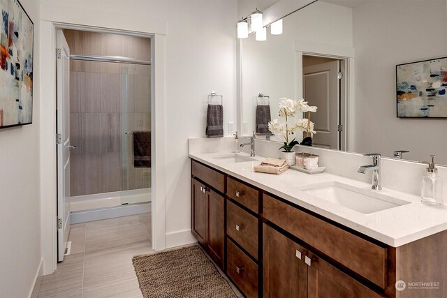 bathroom featuring a sink, a shower stall, baseboards, and double vanity