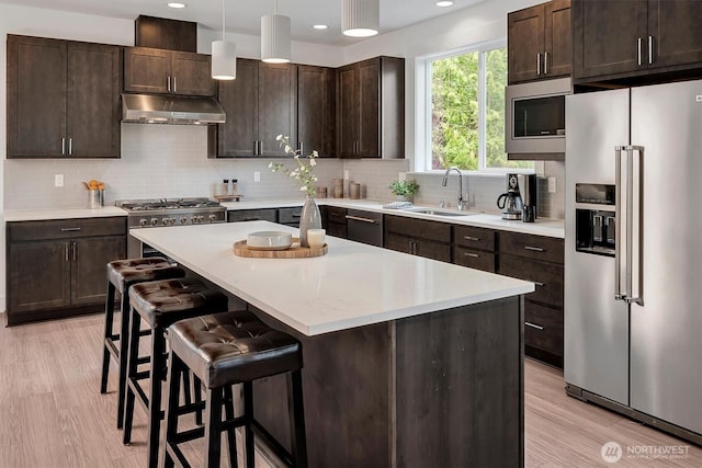 17018 106th Ave SE Unit 11, Renton, WA 98055 - kitchen with high quality appliances, under cabinet range hood, a sink, dark brown cabinetry, and recessed lighting