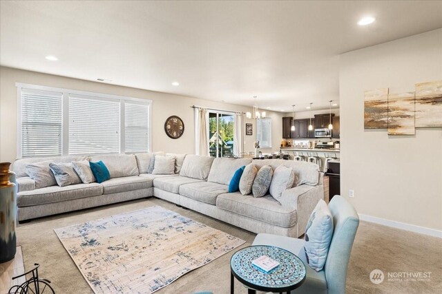 carpeted living room with a notable chandelier