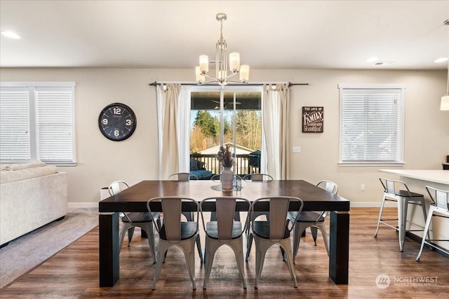 dining space with dark hardwood / wood-style floors and an inviting chandelier