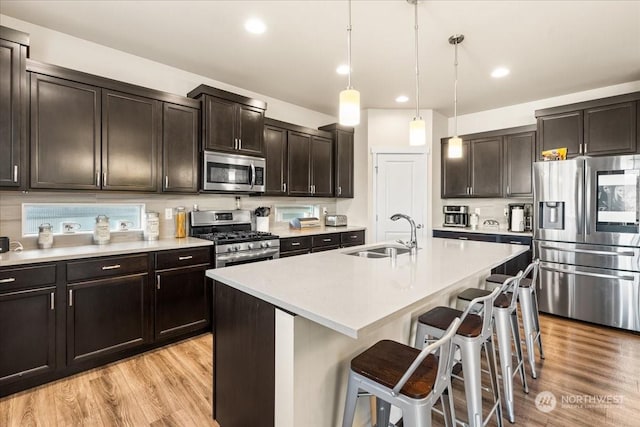 kitchen featuring hanging light fixtures, sink, a breakfast bar, a center island with sink, and stainless steel appliances