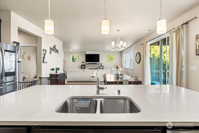 kitchen featuring sink, a kitchen island with sink, and stainless steel fridge