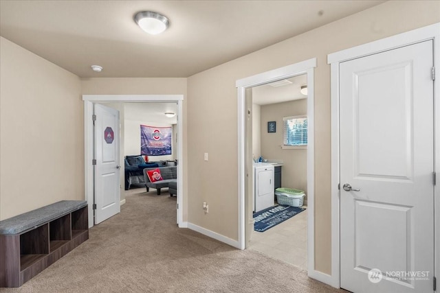 corridor featuring washer / clothes dryer and light colored carpet