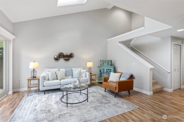 living room with lofted ceiling with skylight and hardwood / wood-style floors