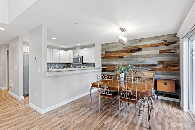 dining space featuring wooden walls and light hardwood / wood-style floors