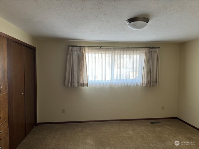 unfurnished bedroom featuring light colored carpet, a closet, and a textured ceiling