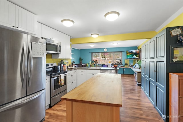 kitchen with white cabinets, appliances with stainless steel finishes, light hardwood / wood-style floors, sink, and kitchen peninsula