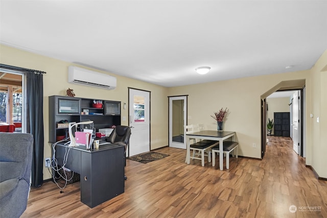 interior space featuring wood-type flooring, a wall unit AC, and a kitchen breakfast bar