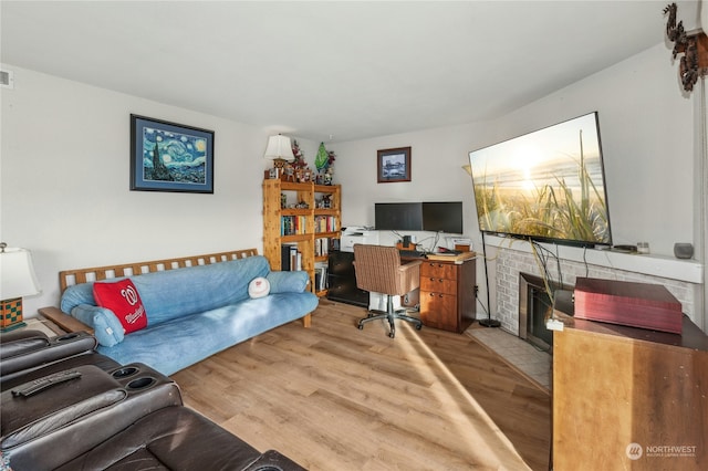 office area with light wood-type flooring and a fireplace