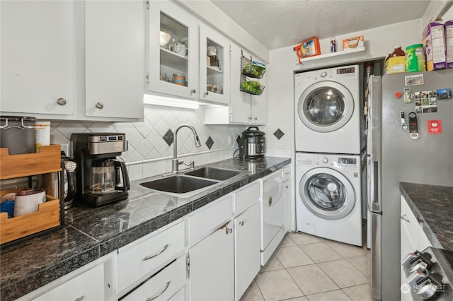 washroom with sink, stacked washer / dryer, and light tile patterned floors