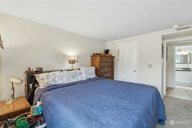 bedroom featuring ensuite bathroom and carpet