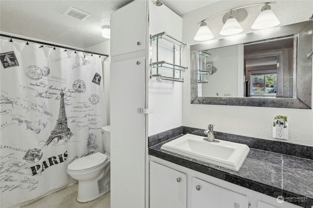 bathroom featuring vanity, toilet, tile patterned floors, and a textured ceiling