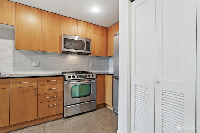 kitchen with stainless steel appliances, light tile patterned flooring, sink, and decorative backsplash