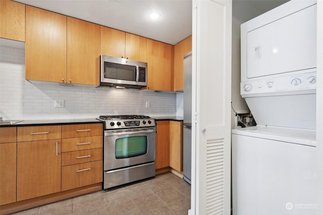 kitchen featuring tasteful backsplash, appliances with stainless steel finishes, stacked washing maching and dryer, and light tile patterned flooring