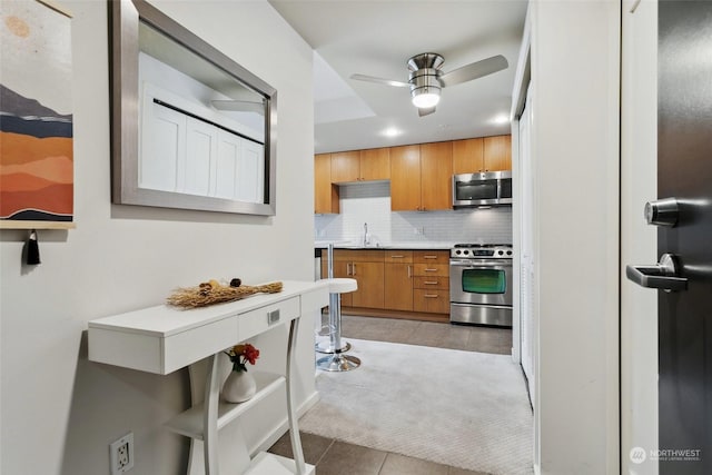 kitchen with sink, ceiling fan, appliances with stainless steel finishes, tasteful backsplash, and light tile patterned flooring