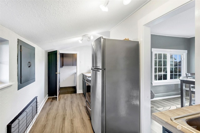 kitchen with vaulted ceiling, appliances with stainless steel finishes, a textured ceiling, and light wood-type flooring