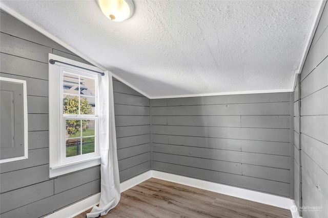 bonus room featuring hardwood / wood-style flooring, wooden walls, and vaulted ceiling