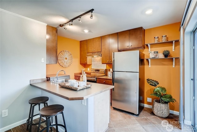 kitchen with kitchen peninsula, rail lighting, a kitchen breakfast bar, and stainless steel appliances