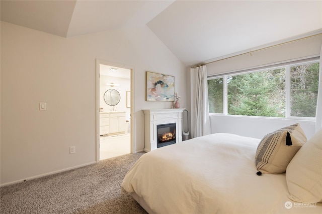 bedroom with carpet floors, connected bathroom, and vaulted ceiling