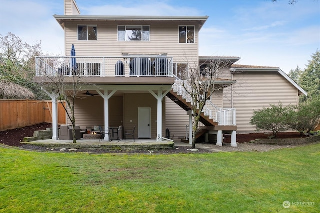 back of house featuring ceiling fan, a deck, a patio, and a lawn