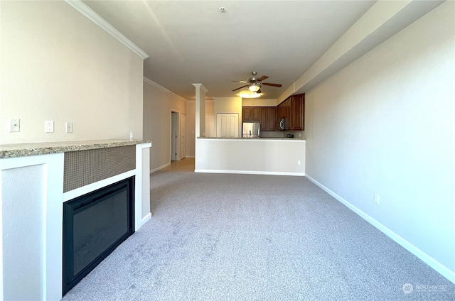 unfurnished living room with light carpet, baseboards, a glass covered fireplace, ceiling fan, and ornamental molding