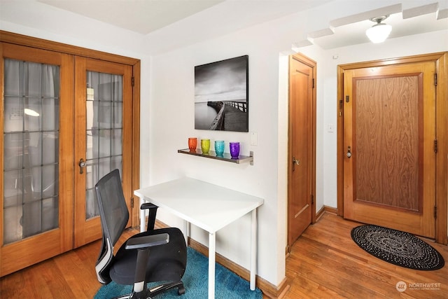 office area with light hardwood / wood-style floors and french doors