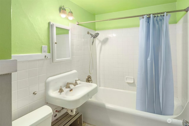 full bathroom featuring toilet, tile walls, sink, shower / bath combination with curtain, and backsplash