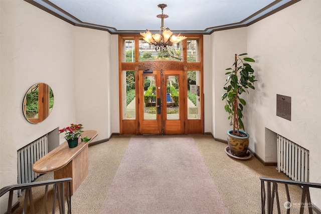 foyer with crown molding, a chandelier, radiator, and french doors