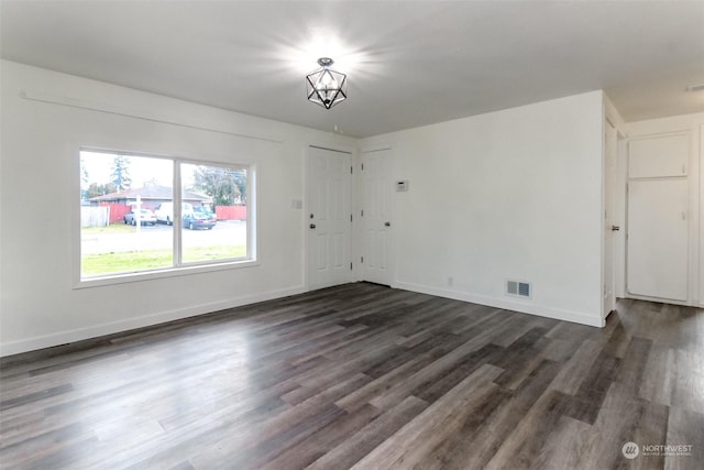 empty room featuring an inviting chandelier and dark hardwood / wood-style floors