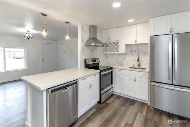 kitchen featuring kitchen peninsula, wall chimney exhaust hood, sink, white cabinets, and stainless steel appliances