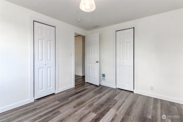 unfurnished bedroom featuring multiple closets and light hardwood / wood-style flooring